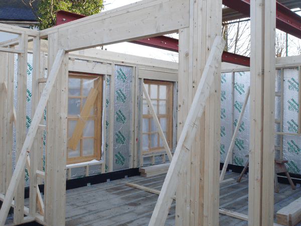 The timber frame's open panels are insulated on site