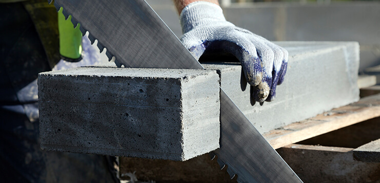 An H+H aircrete concrete block being hand-cut on site