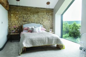 Exposed stonework sits alongside modern apex glazing to offer wonderful views over the countryside from this barn converison. Photo: Colin Poole