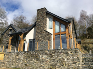 Timber frame home clad in stone and render featuring large expanses of glass