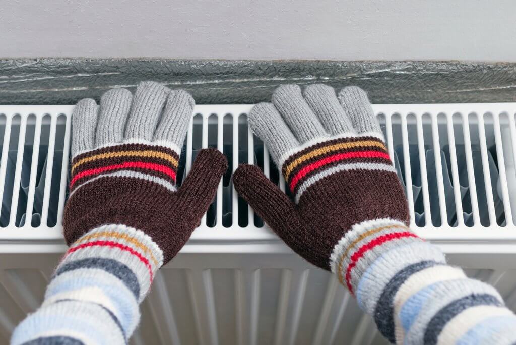 wearing gloves to check for cold spots on a radiator
