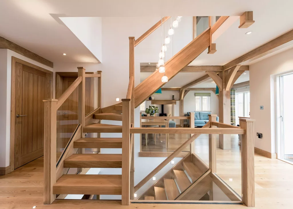 oak frame home with wooden staircase and glass balustrade