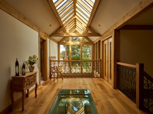 Upper storey hallway in oak frame home with glazed floor and rooflights