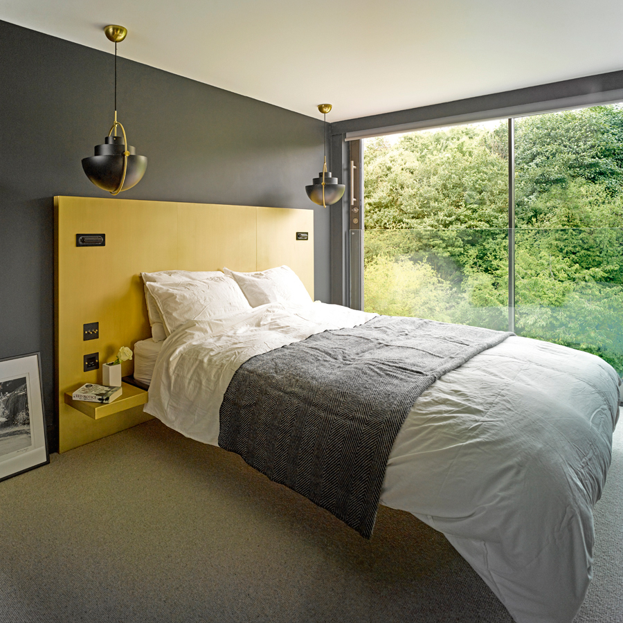 Bed with yellow headboard contrasting grey walls
