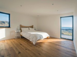 Bedroom with glazed door connecting to the exterior deck, overlooking the sea
