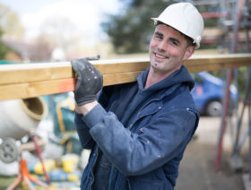 Builder carrying timber planks
