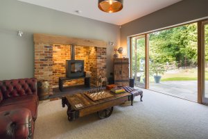 Lounge area with stove and leather sofas opening to garden