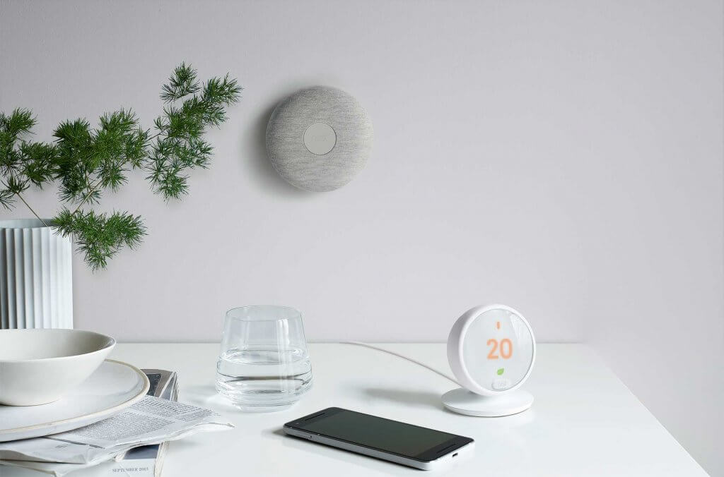 Smart thermostat on a desk next to phone