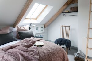 Attic bedroom with exposed beams and neutral colour palette