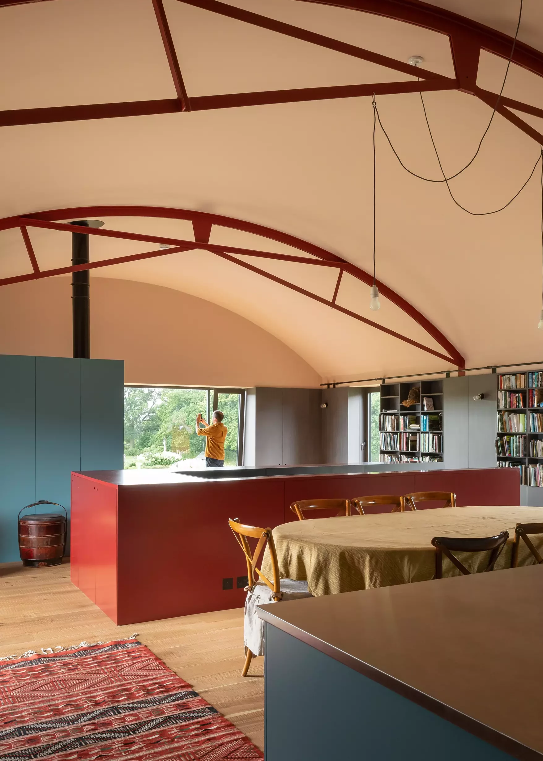 Dutch barn conversion with red and blue surface details and curved vaulted ceiling