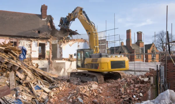 Excavator knocking down old house