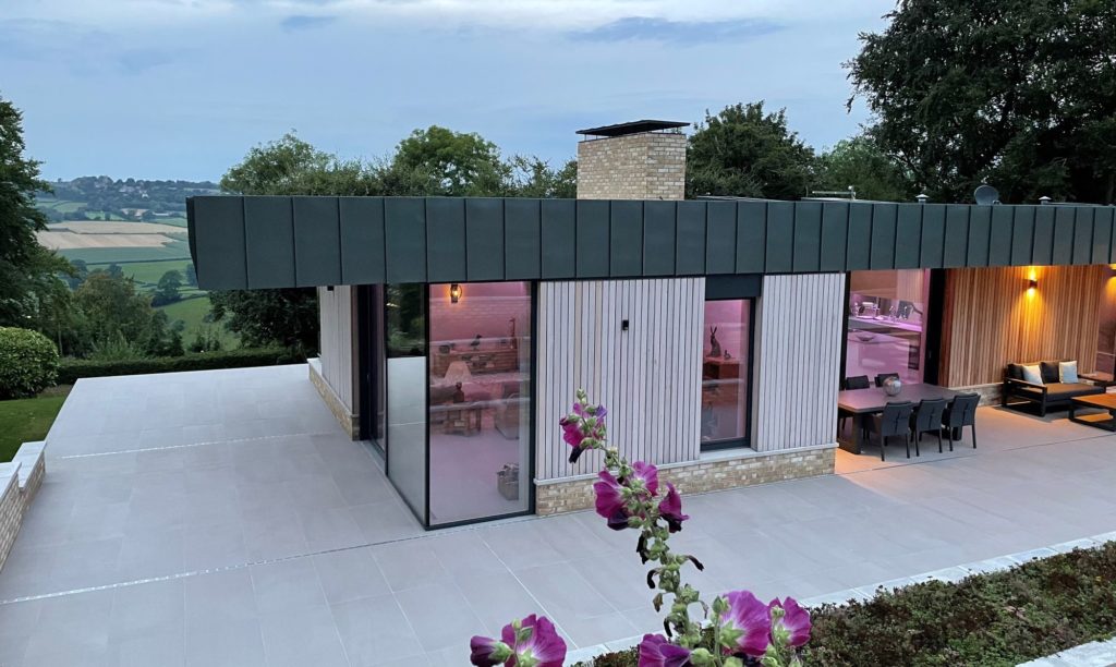 This lift-and-slide door abuts fixed panes that create a glazed corner, offering panoramic views across the rural landscape. When open, the door provides an instant connection to the outside