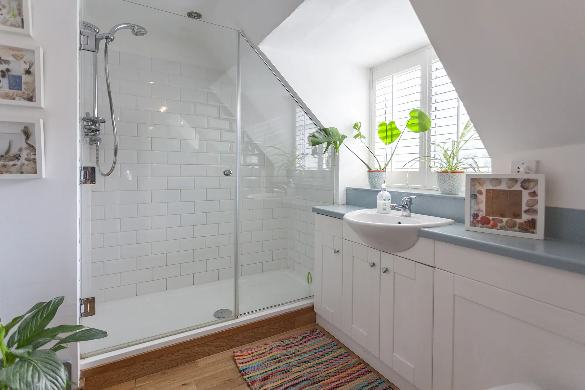White bathroom with sloped ceiling and plants