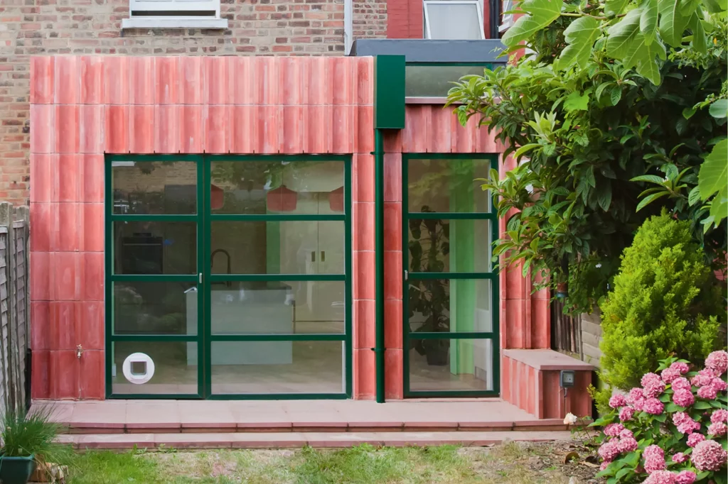 Glazed extension with pink tiles and green frames
