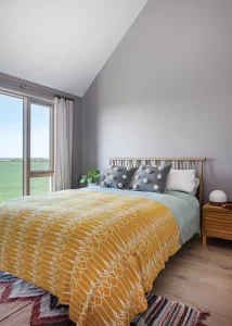 bedroom with vaulted ceiling and large glazing looking out over the farmland