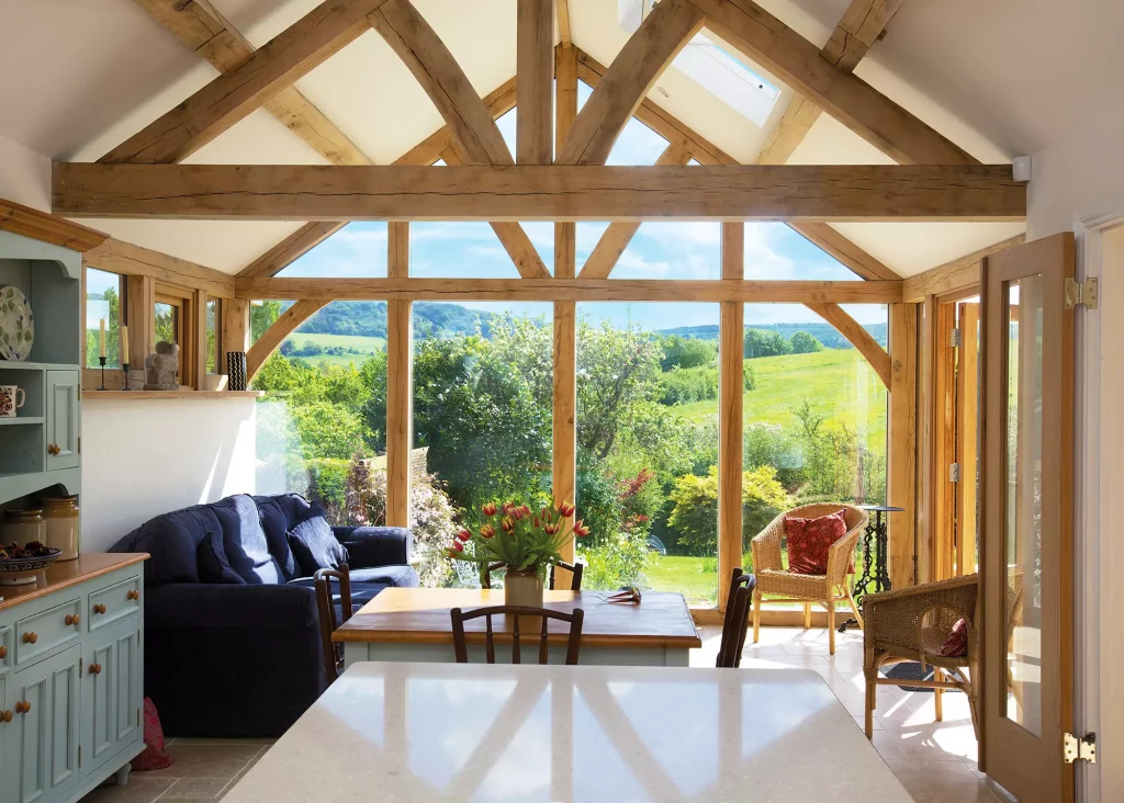 garden room with exposed oak trusses and glazing with views of countryside