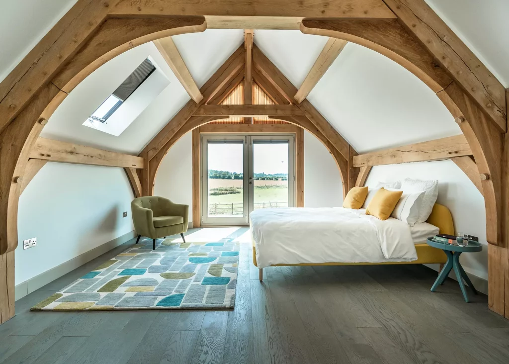 bedroom with arched oak trusses and glazed balcony doors