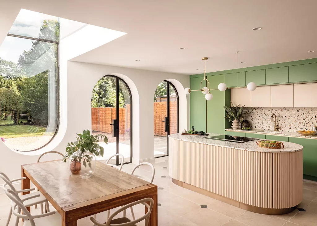 Open plan kitchen-diner extension with green cabinets and curved arch windows