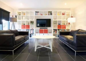 living area with black sofas and large built-in tv and bookshelf