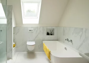 white marble bathroom with rooflight glazing in the vaulted ceiling