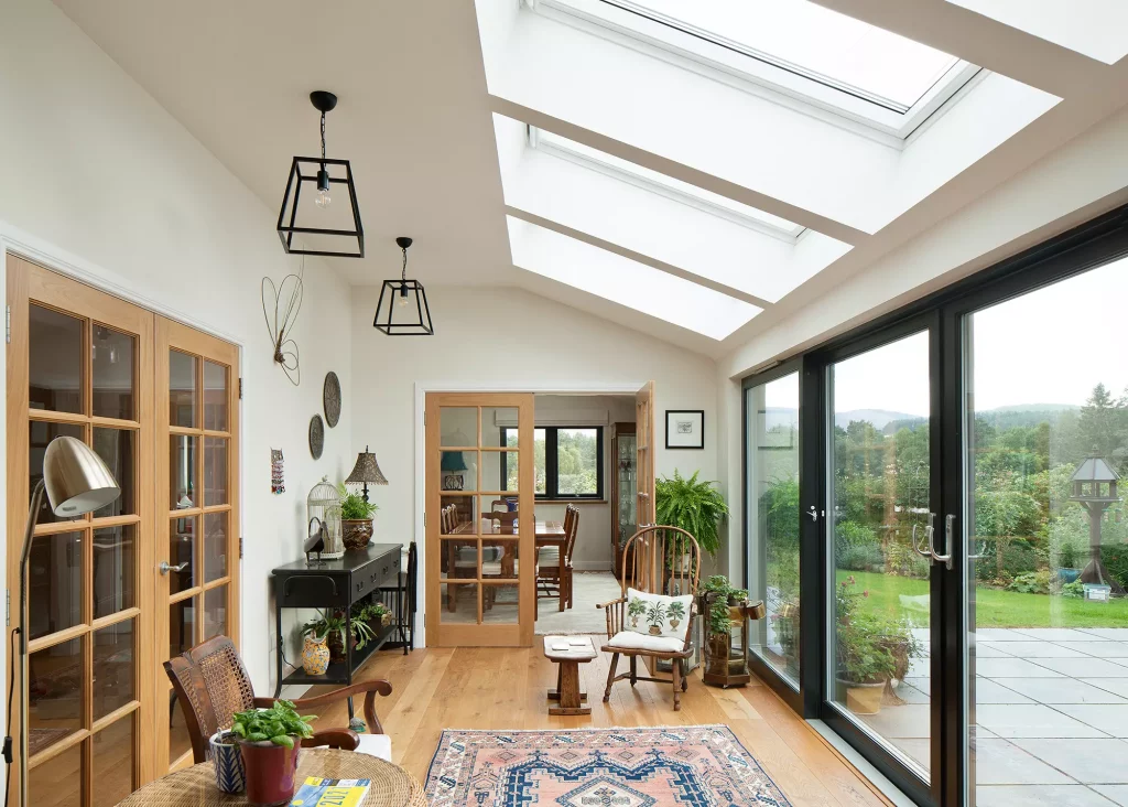 Timber frame home conservatory area with rooflight glazing and full-height glazed doors looking out over the garden