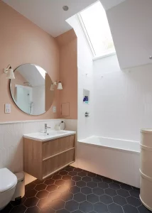 peach-coloured bathroom with rooflight and geometric floor tiling