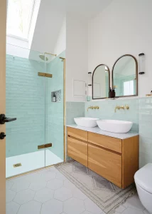 light-filled bathroom with blue tiles, walki-in shower and his-and-hers sinks