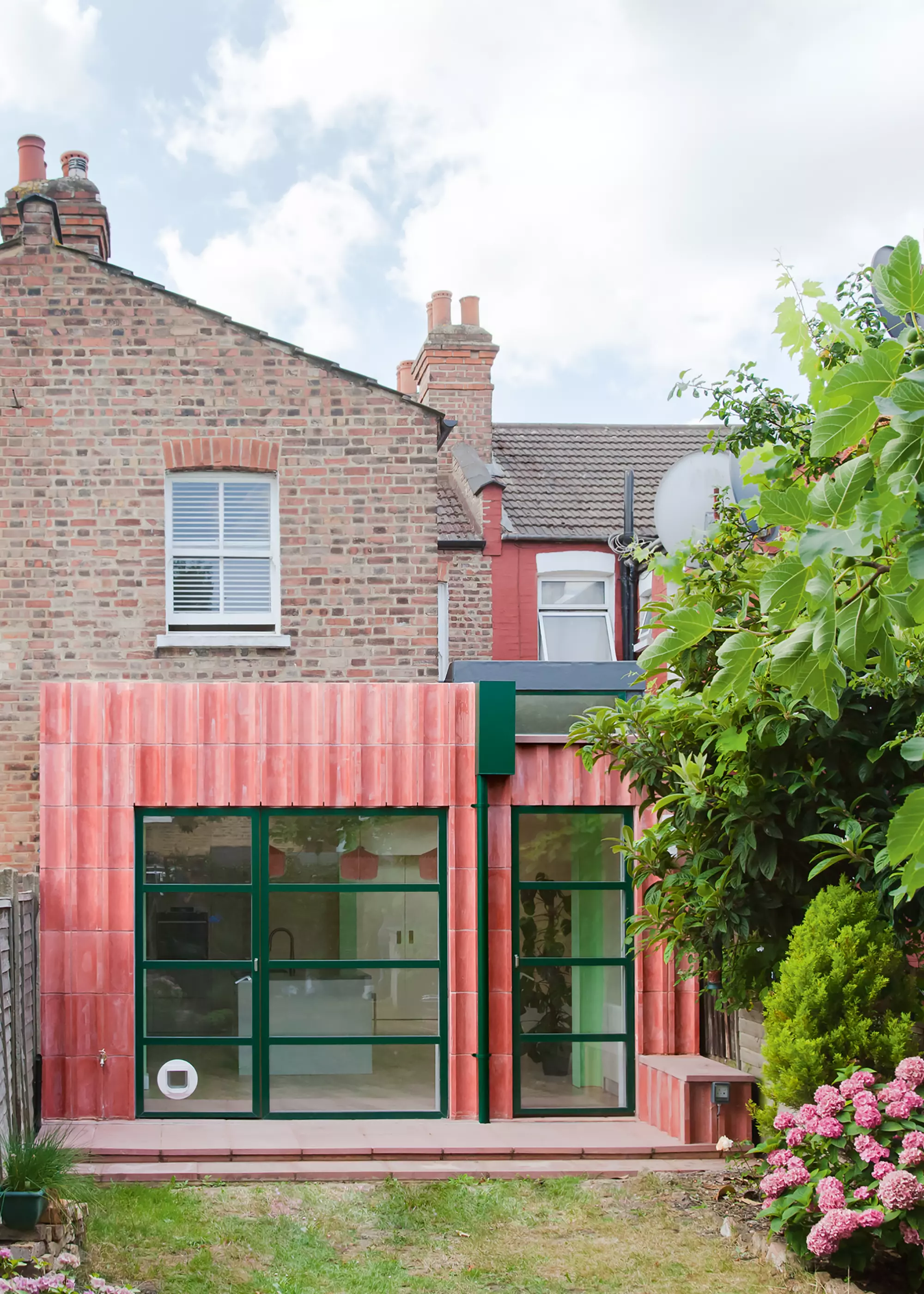 rear home extension finished with red concrete blocks and glazing with dark green framing