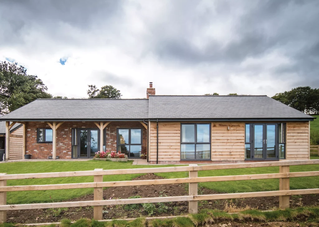 rear exterior shot of the brick and block bungalow, finished in oak cladding and mixed toned brickwork