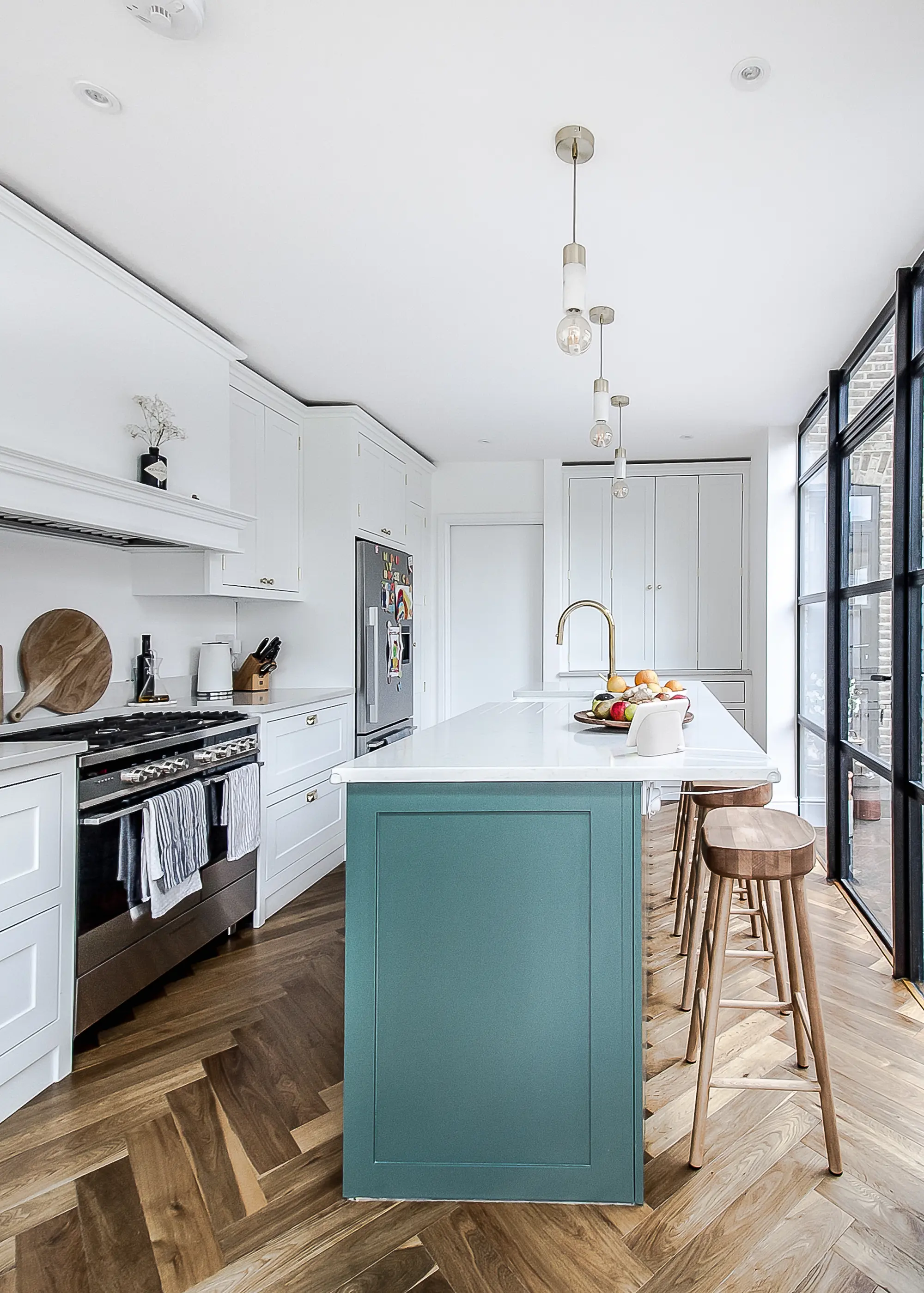 White kitchen with oak herringbone floor, turquoise island and bar stool seating